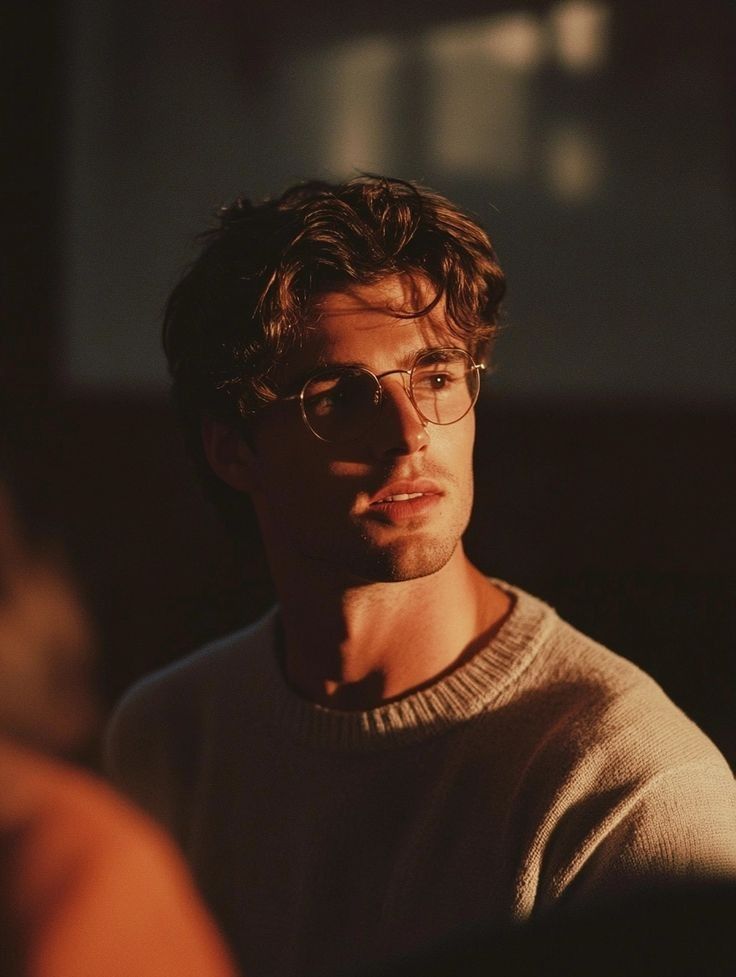 A black and white portrait of Kevin sitting a chair with his legs crossed.
